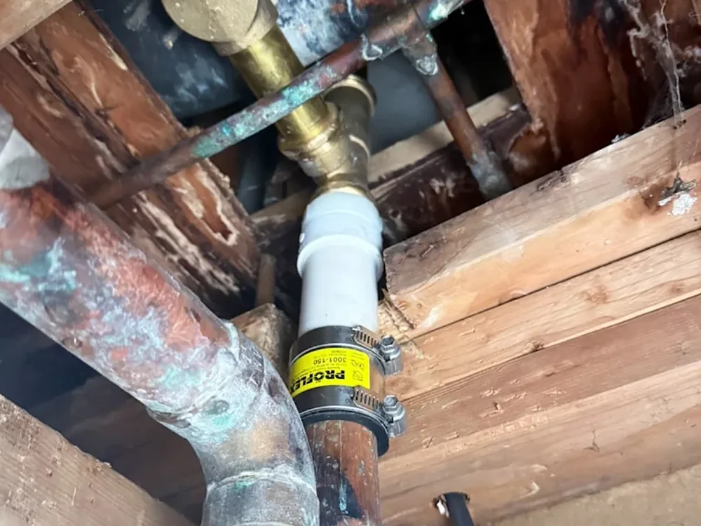 Copper water line repaired with a press coupling in a floor joist bay